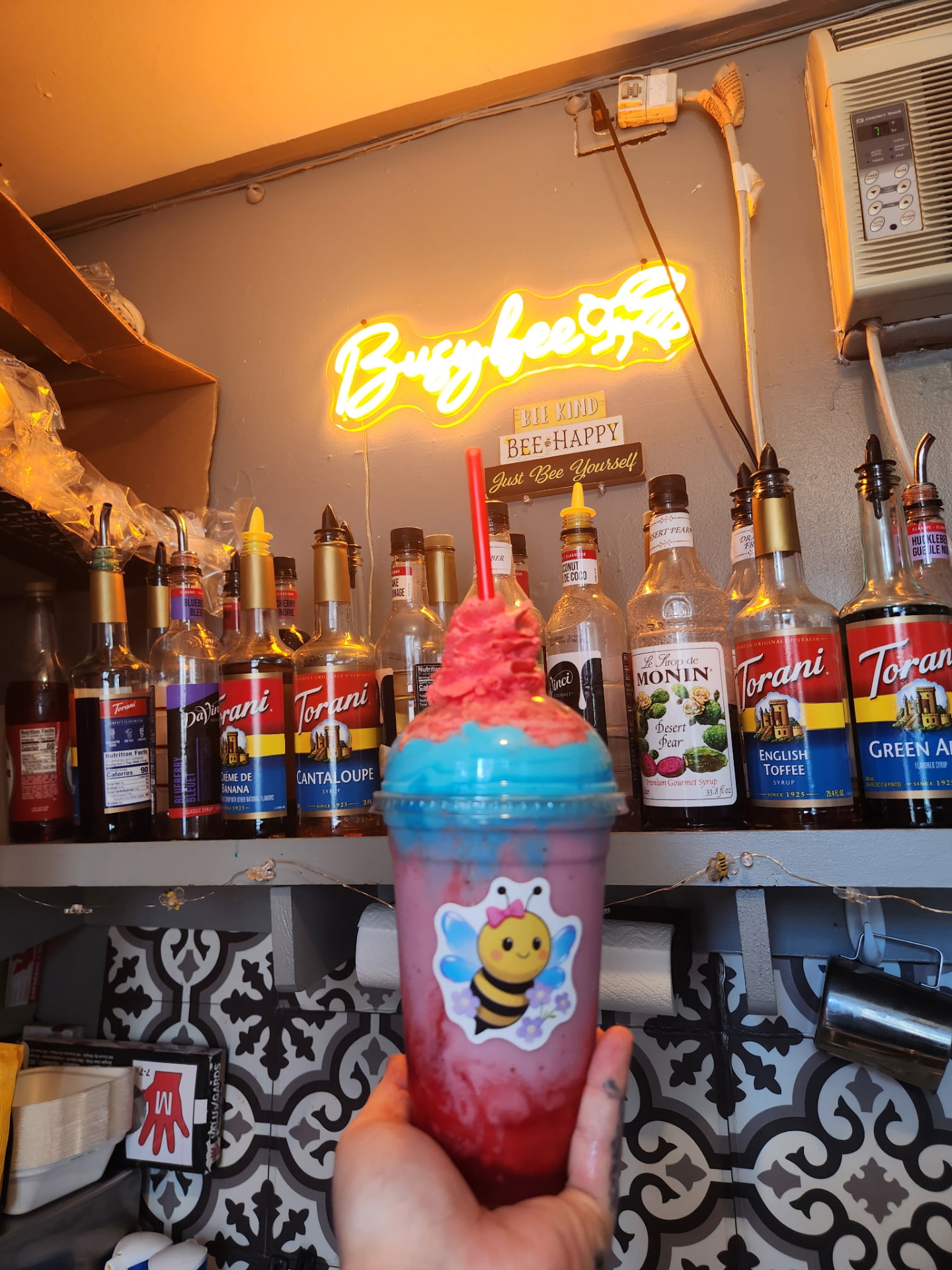 Berry blue freeze drink with a red straw in front of the espresso syrup shelf